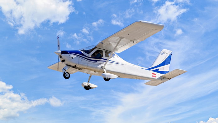 Single engine ultralight plane flying in the blue sky with white clouds