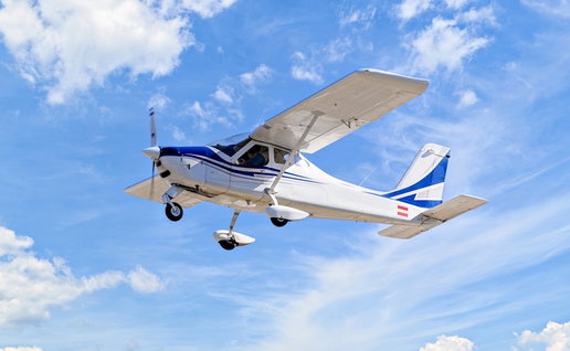 Single engine ultralight plane flying in the blue sky with white clouds