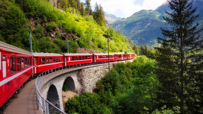 Red train moving in beautiful mountain landscape.