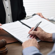 Senior man signing document in lawyer's office, closeup.