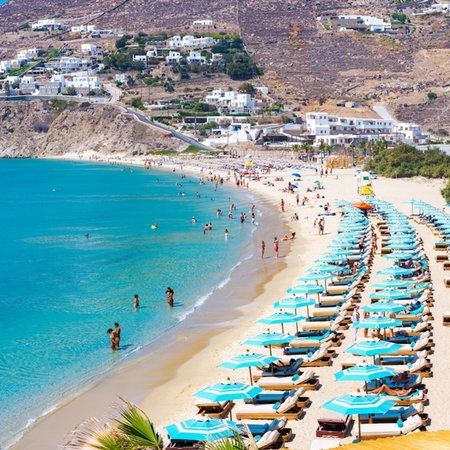 Mykonos, Greece - beach full of sun-loungers and crystal blue water