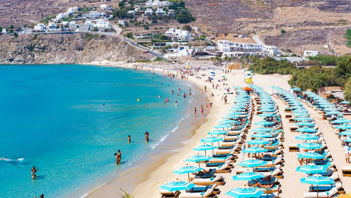 Mykonos, Greece - beach full of sun-loungers and crystal blue water