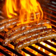 Grilling sausages on the grill with flames and smoke.