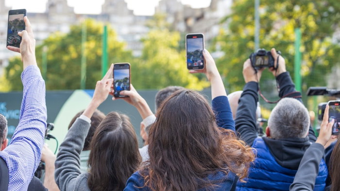 Crowd of people raising smartphones and cameras to capture an event/incident