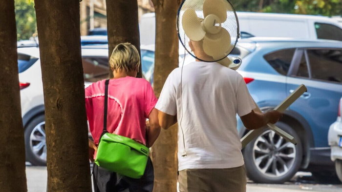 Woman and man carrying electric fan in street