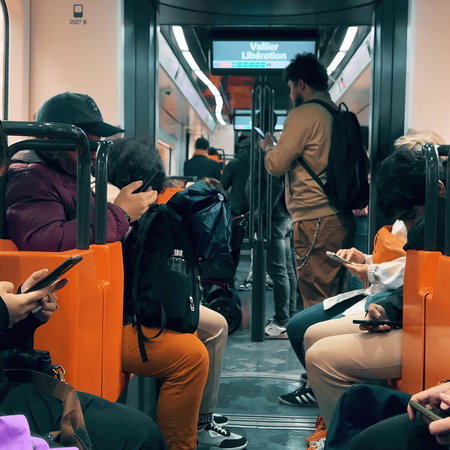 Youths sitting on an underground train looking at their smartphones