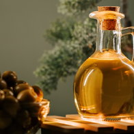 Olive oil in a glass bottle beside a bowl of olives on a wooden surface