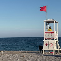 Lifeguard tower with lifeguard on duty at beach with clear blue sea
