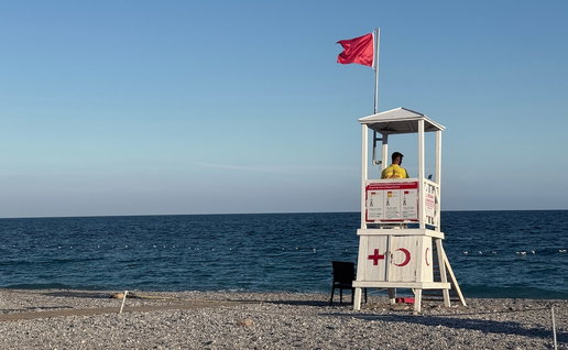 Lifeguard tower with lifeguard on duty at beach with clear blue sea