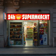 A brightly lit 24 hour supermarket open at night in Barcelona city centre.