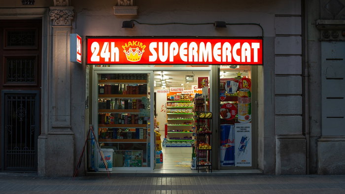 A brightly lit 24 hour supermarket open at night in Barcelona city centre.