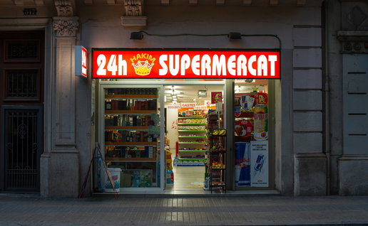 A brightly lit 24 hour supermarket open at night in Barcelona city centre.