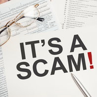 A tax scam warning displayed over tax return documents and paperwork, illustrating fraudulent messages that impersonate tax authorities to steal personal and banking information.