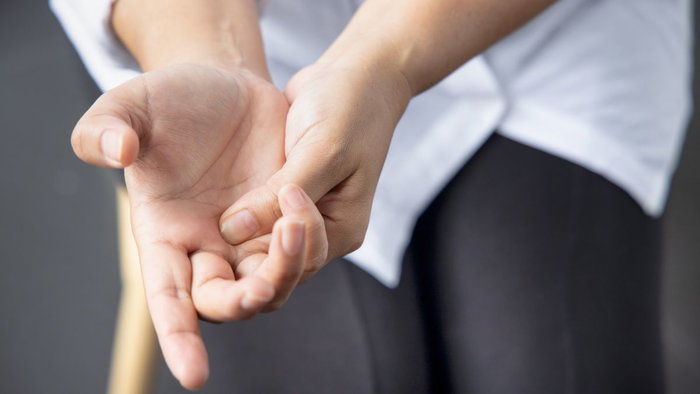 A close-up shot of a person massaging the palm of their hand to relieve tension and pain.