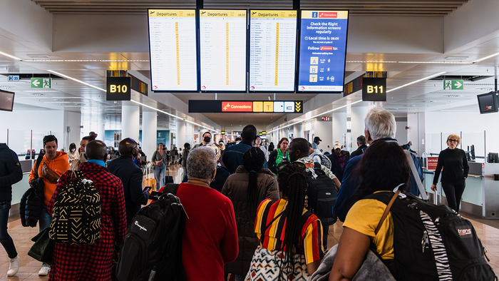 People gather around monitor screens at airport.