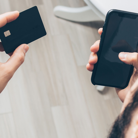 Person holding a credit card and phone in their hands ready to use them together.