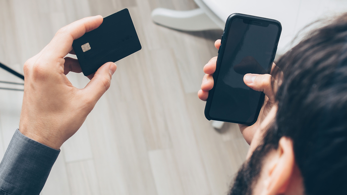 Person holding a credit card and phone in their hands ready to use them together.