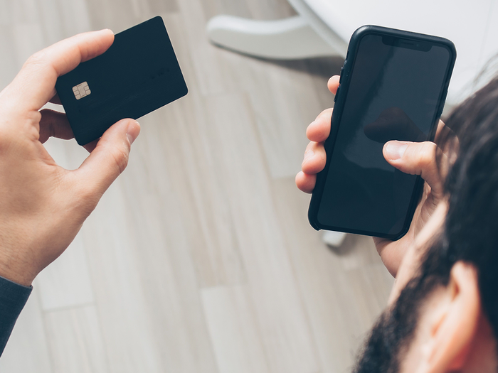 Person holding a credit card and phone in their hands ready to use them together.