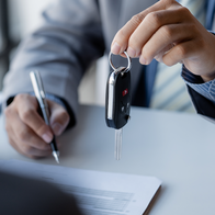 Person handing over keys at the reception of a car hire office.