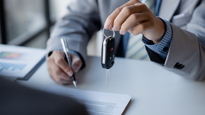 Person handing over keys at the reception of a car hire office.