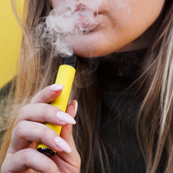 Young girl smokes colourful vape.