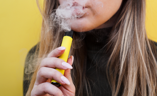 Young girl smokes colourful vape.