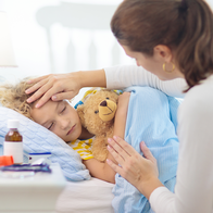 Parent caring for sick child in bed.