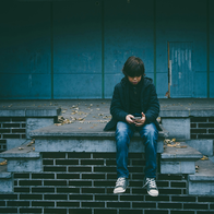 Child sat alone staring at phone in hand
