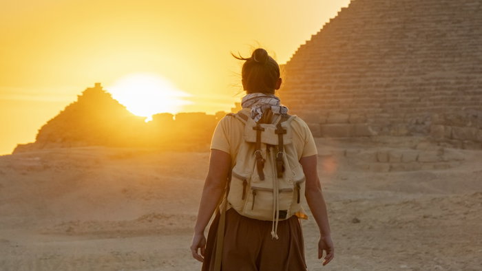 Person walking towards the sunset near the Pyramids of Egypt