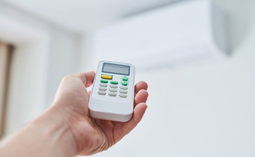 View of a hand holding a remote control for a air-conditioning unit