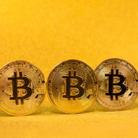 3 gold bitcoins with a shiny gold background