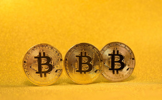 3 gold bitcoins with a shiny gold background