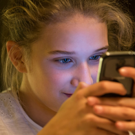 Young girl looks intently at her phone.