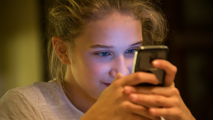 Young girl looks intently at her phone.