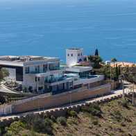 Luxury villa on top of a hill with the sea in the background.