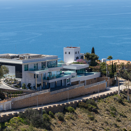 Luxury villa on top of a hill with the sea in the background.