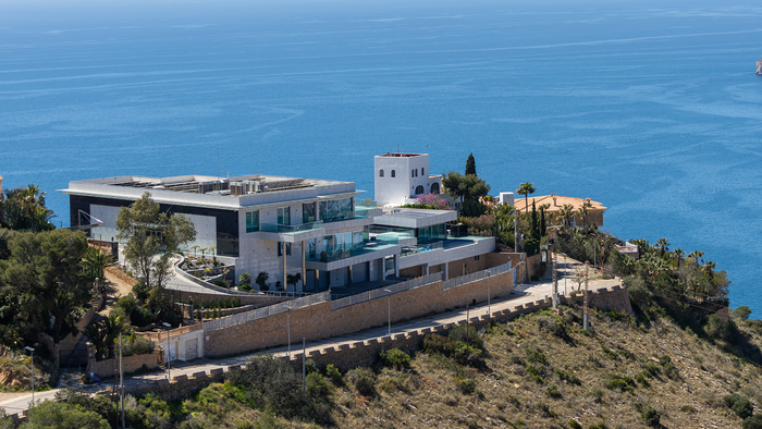 Luxury villa on top of a hill with the sea in the background.