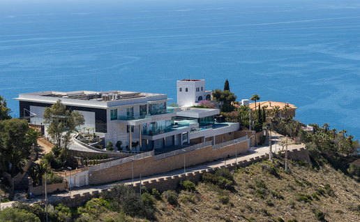 Luxury villa on top of a hill with the sea in the background.