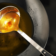 Kitchen ladle in frying pan with old olive oil.