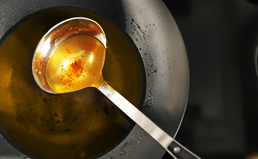 Kitchen ladle in frying pan with old olive oil.