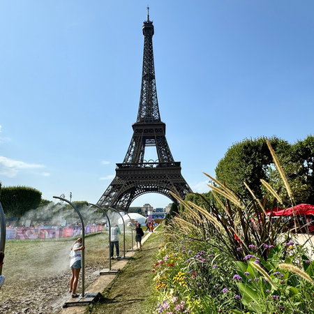 People cool off under water mist sprays near the Eiffel Tower during an intense heatwave in Paris.