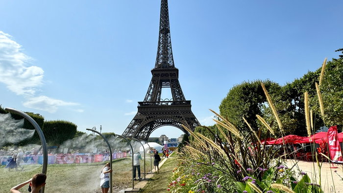 People cool off under water mist sprays near the Eiffel Tower during an intense heatwave in Paris.
