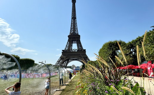 People cool off under water mist sprays near the Eiffel Tower during an intense heatwave in Paris.