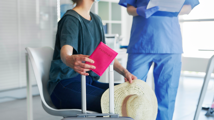 A woman in a hospital waiting room with her passport talking to a doctor