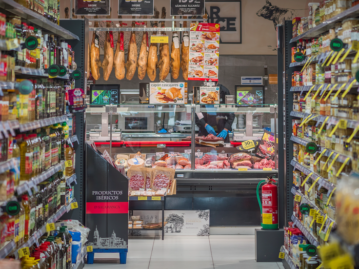 An aisle in a supermarket with the butchers at the end