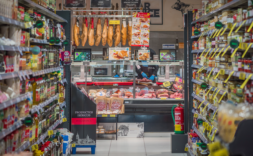 An aisle in a supermarket with the butchers at the end