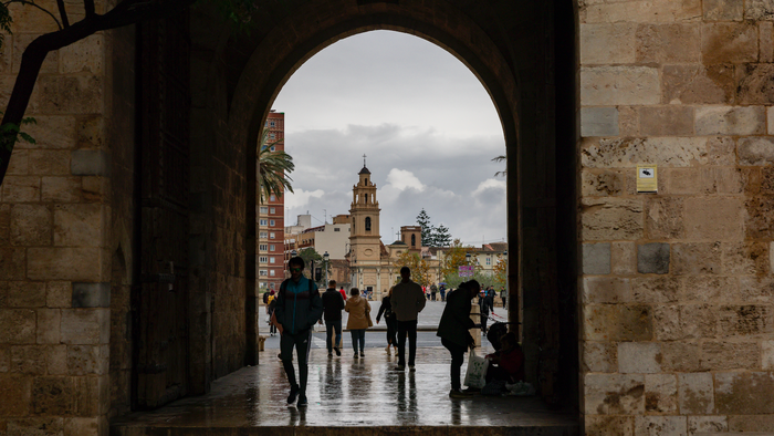 An arch doorway leading to a busy street on a rainy day