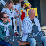 Doctors sitting down during a protest holding banners in shape of a cross