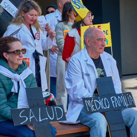 Doctors sitting down during a protest holding banners in shape of a cross