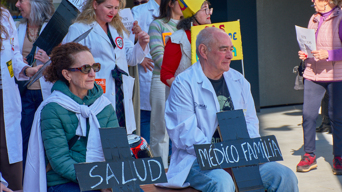 Doctors sitting down during a protest holding banners in shape of a cross